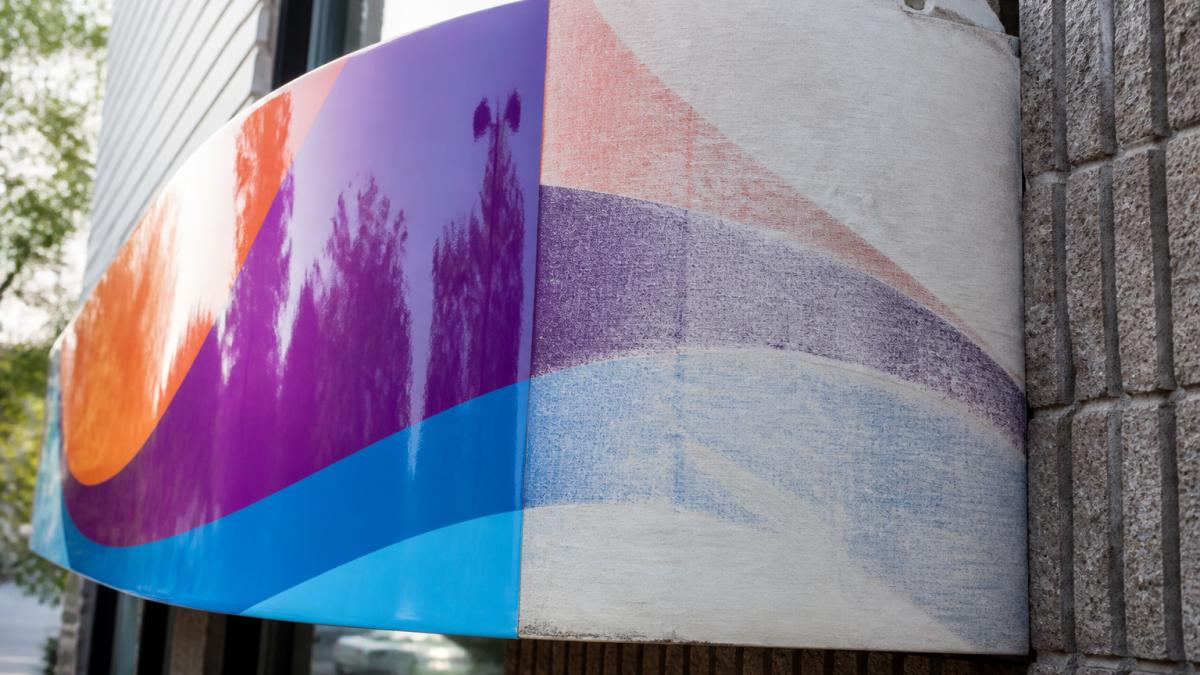 Close-up of an outdoor storefront sign with vibrant colors and glossy protective finish, showing the contrast between a well-coated section and a weathered, faded area without protection